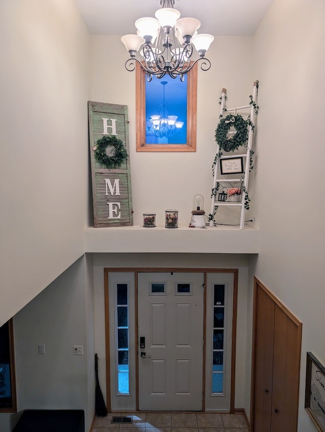 tiled foyer entrance featuring a chandelier