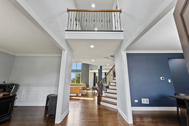 foyer featuring a towering ceiling, ornamental molding, and dark hardwood / wood-style floors