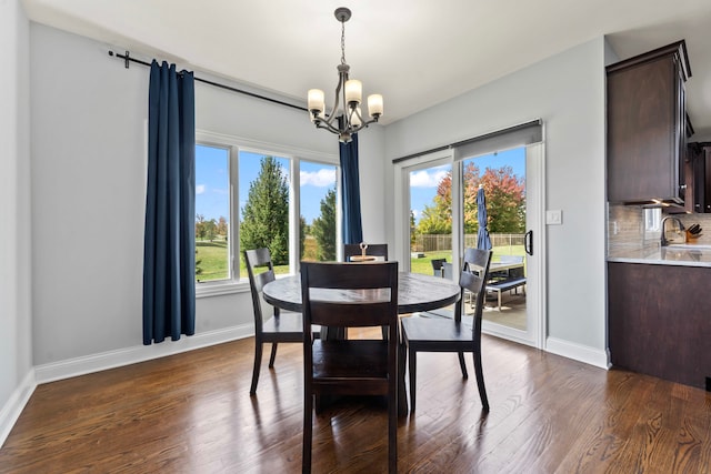 dining space featuring sink, dark hardwood / wood-style floors, and an inviting chandelier