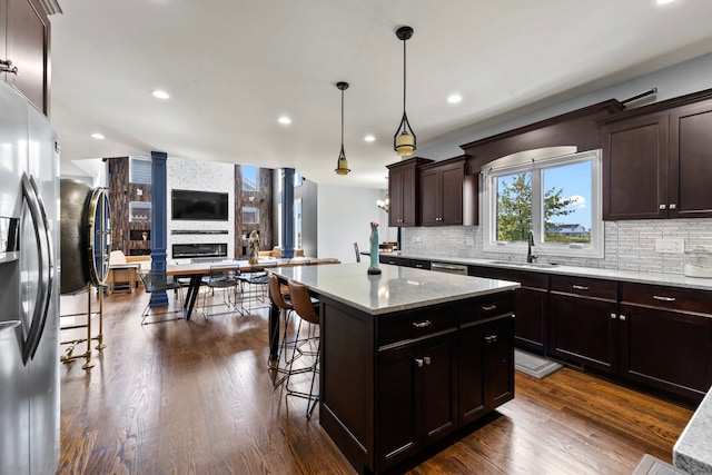 kitchen with a kitchen breakfast bar, dark hardwood / wood-style flooring, stainless steel refrigerator with ice dispenser, and a kitchen island