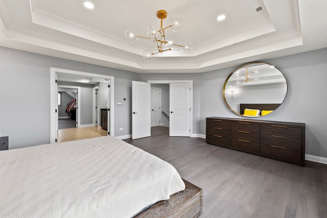 bedroom with dark wood-type flooring, an inviting chandelier, and a raised ceiling