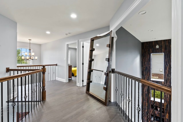 hallway with an inviting chandelier, hardwood / wood-style floors, and wooden walls