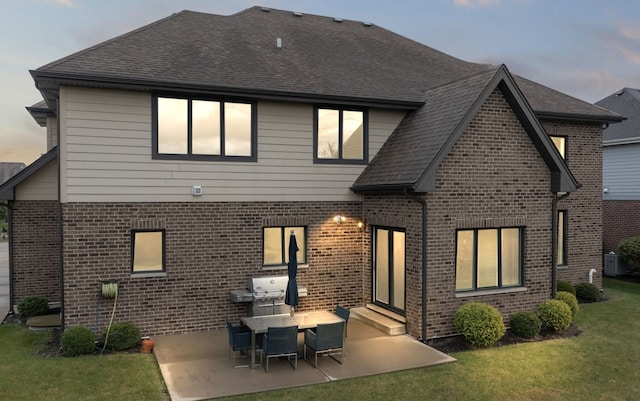 back house at dusk featuring a yard, a patio area, and cooling unit