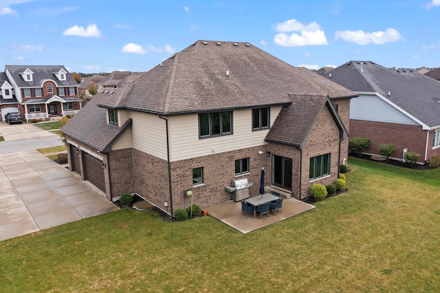 back of house featuring a patio, a yard, and a garage