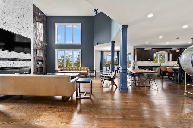 living room with dark wood-type flooring and decorative columns