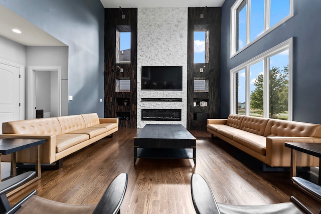 living room with a towering ceiling, a fireplace, and hardwood / wood-style floors