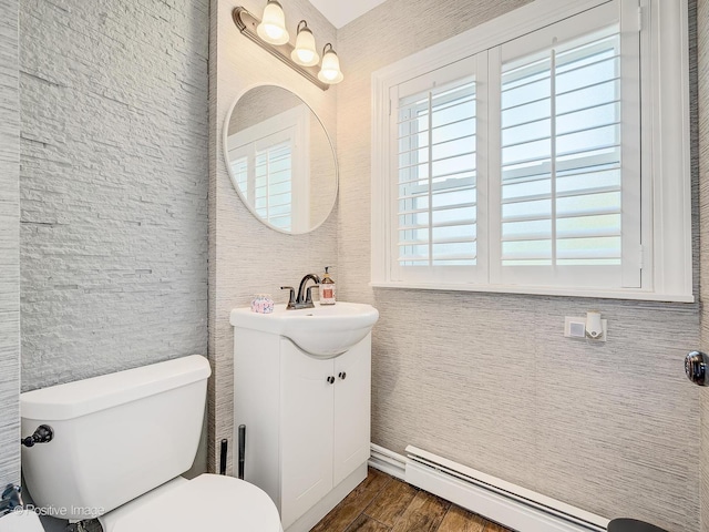 bathroom with vanity, hardwood / wood-style flooring, toilet, and baseboard heating