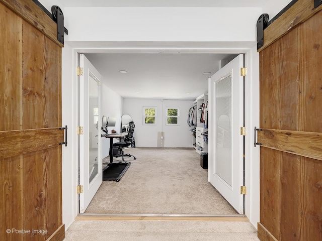 interior space with a barn door and light carpet