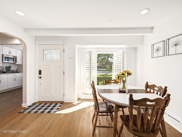 dining room with beam ceiling, light hardwood / wood-style floors, and baseboard heating