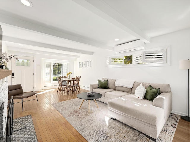 living room featuring a wall unit AC, a fireplace, beamed ceiling, and wood-type flooring