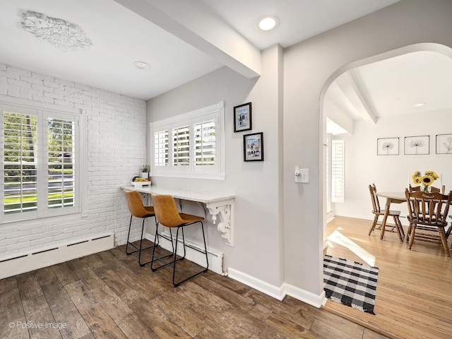 office space with dark hardwood / wood-style flooring, brick wall, and plenty of natural light