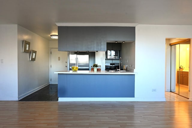 kitchen featuring built in microwave, wood-type flooring, kitchen peninsula, and stainless steel refrigerator