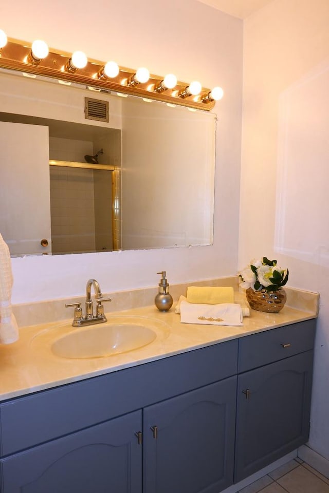 bathroom with a shower with shower door, tile patterned floors, and vanity