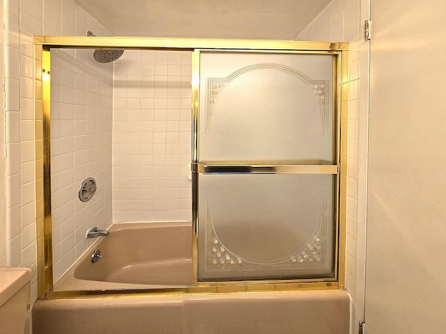 bathroom with combined bath / shower with glass door and toilet