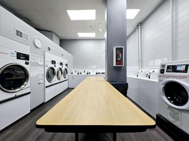 laundry area with dark hardwood / wood-style floors, washing machine and dryer, stacked washer and clothes dryer, and a skylight