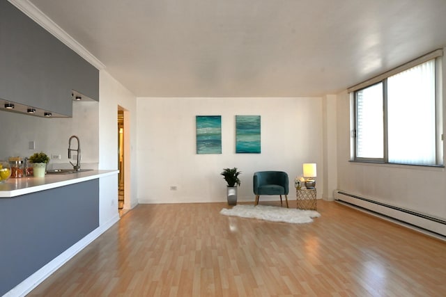 sitting room featuring sink, light hardwood / wood-style flooring, a baseboard radiator, and ornamental molding