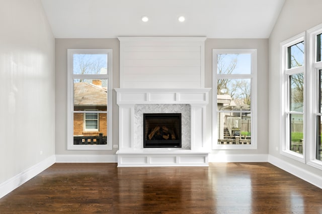 unfurnished living room with dark hardwood / wood-style flooring, a premium fireplace, and plenty of natural light