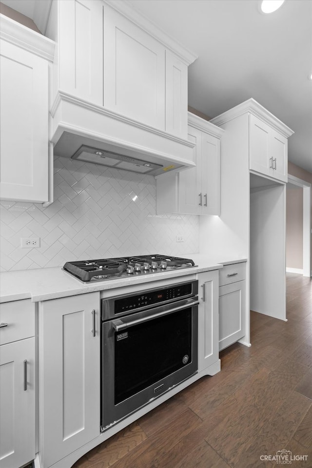 kitchen featuring appliances with stainless steel finishes, backsplash, white cabinetry, and dark hardwood / wood-style floors