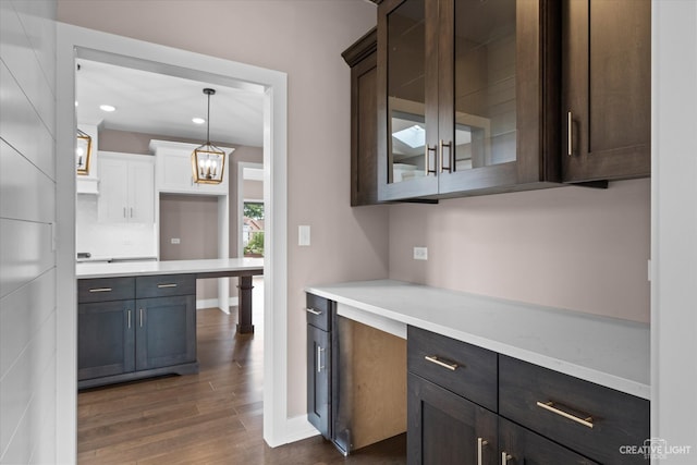 kitchen featuring dark brown cabinetry, hanging light fixtures, and dark wood-type flooring