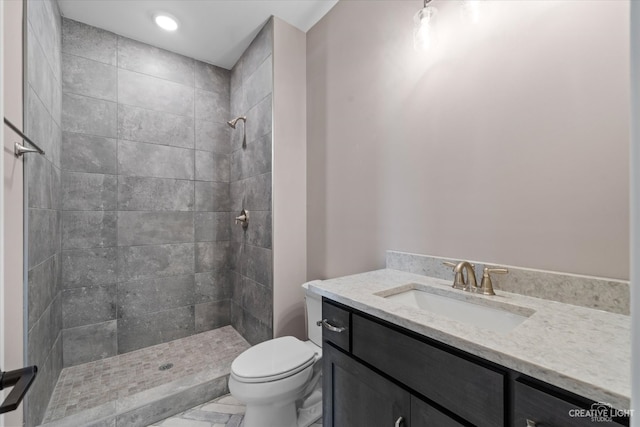 bathroom featuring tiled shower, vanity, and toilet