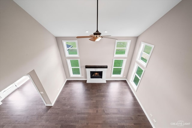 unfurnished living room with ceiling fan and dark wood-type flooring