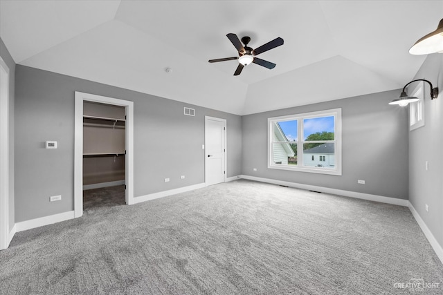 unfurnished bedroom featuring a closet, lofted ceiling, carpet floors, a spacious closet, and ceiling fan