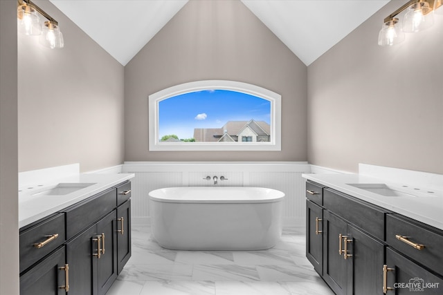 bathroom with vanity, lofted ceiling, and a bathtub