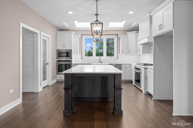 kitchen with dark wood-type flooring, white cabinets, a kitchen island, stainless steel appliances, and a skylight