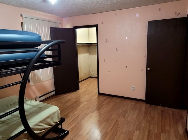 bedroom with light wood-type flooring, a closet, a walk in closet, and a textured ceiling