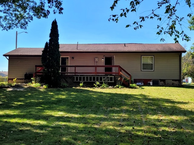 rear view of house featuring a wooden deck and a yard