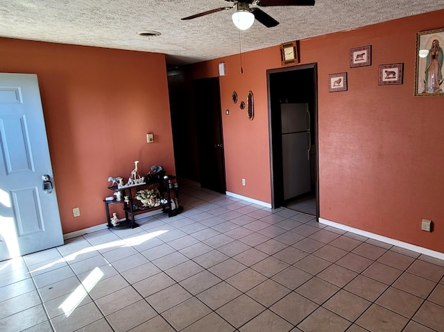 unfurnished room featuring ceiling fan, light tile patterned floors, and a textured ceiling