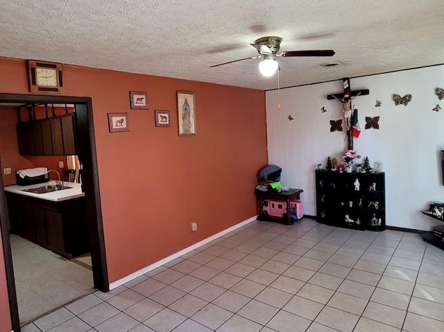 interior space featuring a textured ceiling, light tile patterned flooring, sink, and ceiling fan