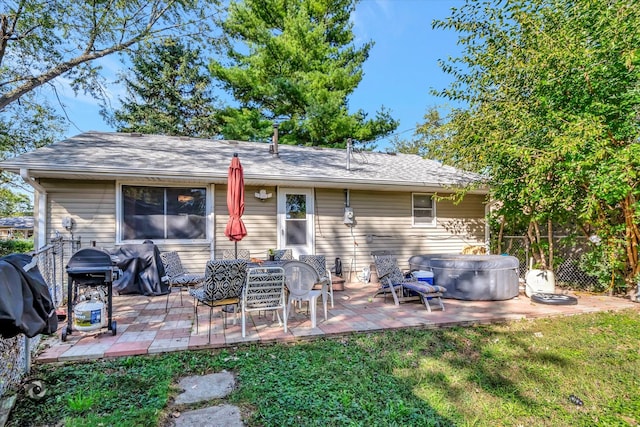 rear view of property featuring a patio, a yard, and a hot tub