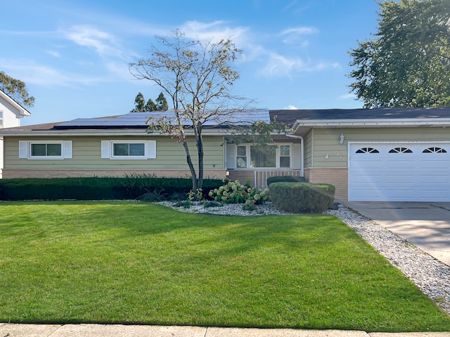 ranch-style home with a garage, solar panels, and a front lawn