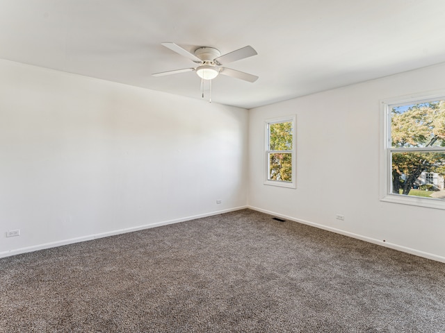 unfurnished room with ceiling fan and dark colored carpet