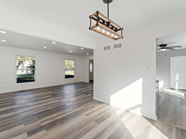 empty room with ceiling fan with notable chandelier and hardwood / wood-style floors