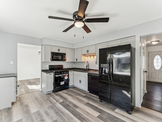 kitchen with ceiling fan, black appliances, sink, and light wood-type flooring