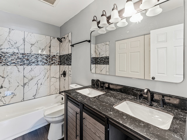 full bathroom with toilet, tiled shower / bath, hardwood / wood-style floors, and vanity