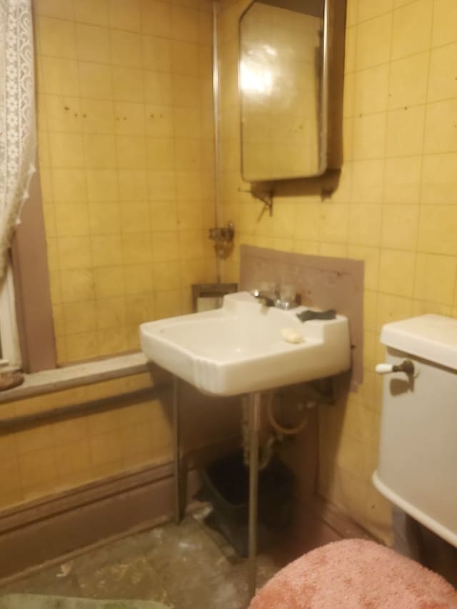 bathroom with tile walls, sink, and toilet