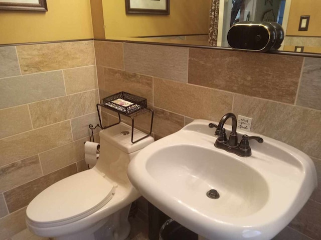 bathroom with tile walls, toilet, and sink