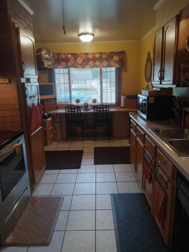 kitchen featuring brick wall, sink, stainless steel appliances, and light tile patterned floors