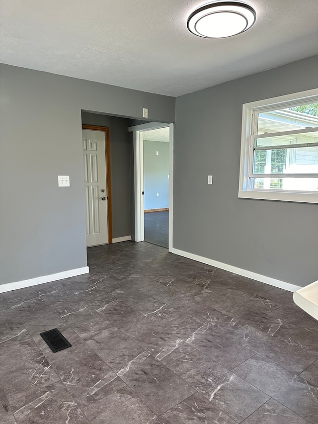 unfurnished room with a textured ceiling