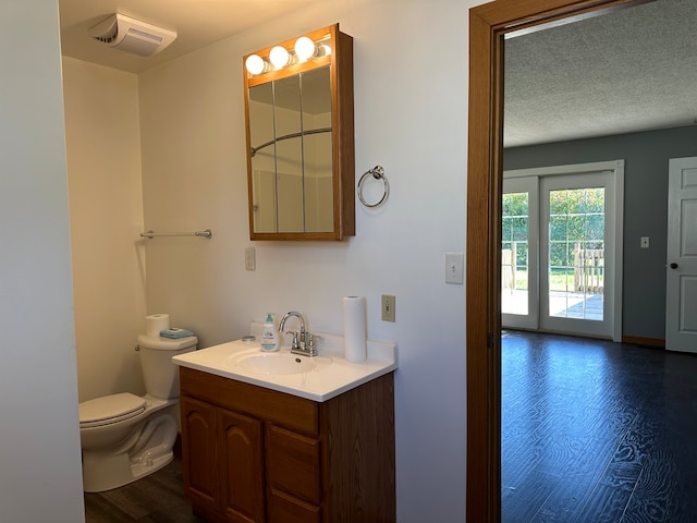 bathroom with vanity, toilet, hardwood / wood-style flooring, and a textured ceiling