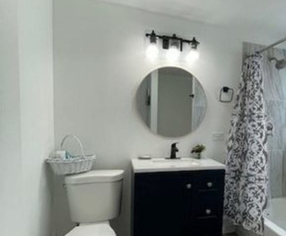 full bathroom with shower / tub combo, vanity, and toilet