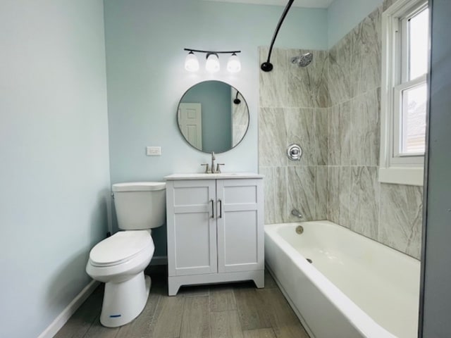 full bathroom featuring hardwood / wood-style floors, tiled shower / bath combo, vanity, and toilet