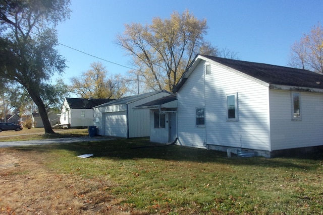 back of property with a garage and a lawn