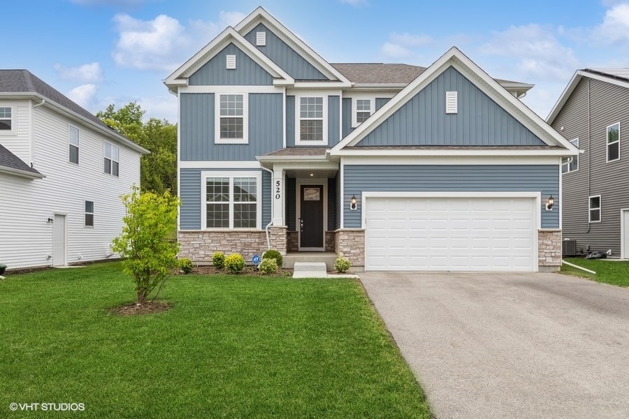 craftsman inspired home featuring cooling unit, a front lawn, and a garage