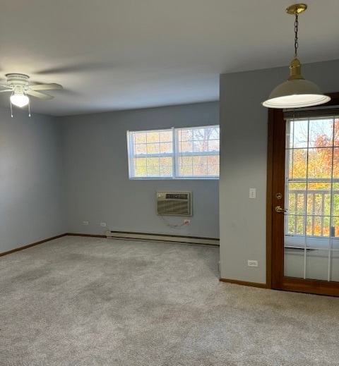 carpeted empty room featuring ceiling fan, a wall mounted AC, and baseboard heating