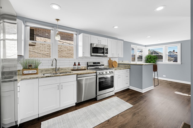 kitchen featuring appliances with stainless steel finishes, hanging light fixtures, sink, and white cabinets