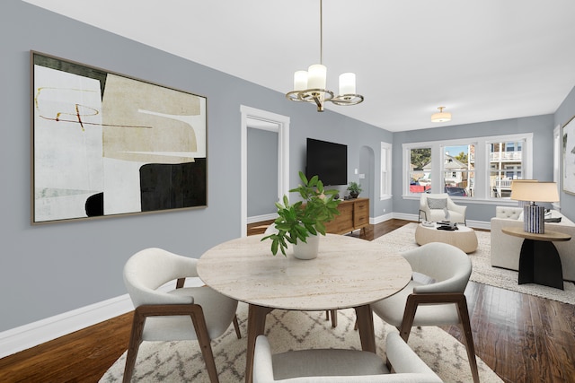 dining space with wood-type flooring and an inviting chandelier